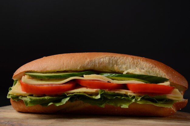 Sandwiches with cheese, lettuce, tomatoes and onion on a on a dark background