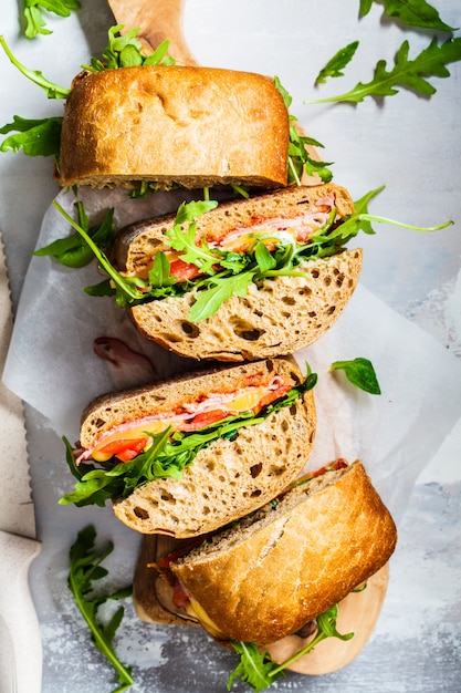 Sandwiches with ciabatta, ham and vegetables on a wooden board