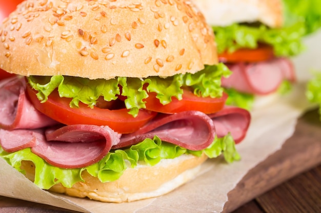 Sandwiches with ham and tomatoes on a wooden background