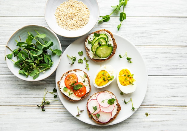 Sandwiches with healthy vegetables and micro greens on a wooden table