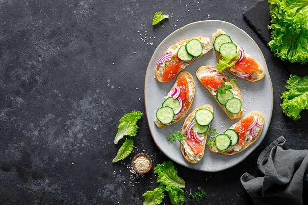 Photo sandwiches with homemade ciabatta bread salted salmon fish feta cheese cucumber onion and fresh lettuce salad