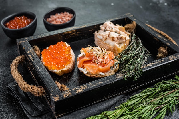 Sandwiches with Hot Smoked salmon and red caviar,  toast bread with cream cheese. Black background. Top view.