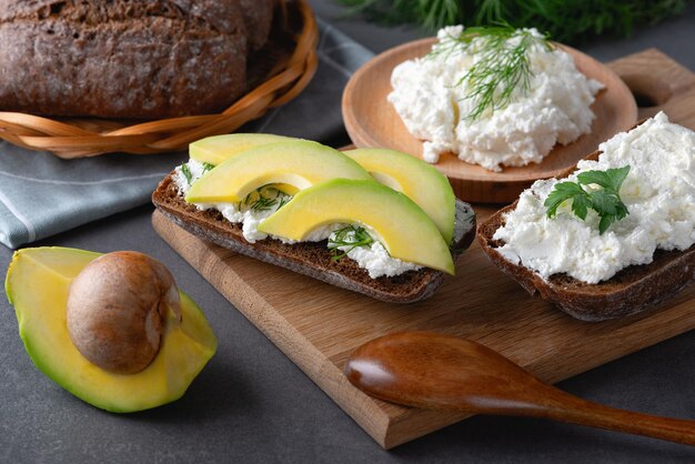 Photo sandwiches with a minced curd avocado and herbs on the natural wooden cutting board