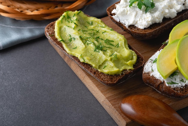 Sandwiches with a minced curd avocado and herbs on the natural wooden cutting board