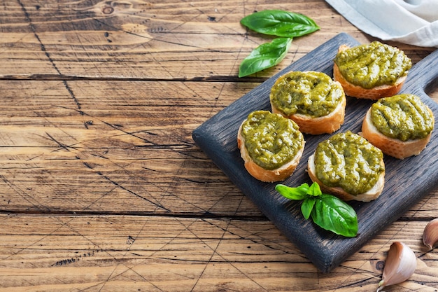 Sandwiches with pesto sauce fresh basil leaves and garlic A delicious healthy snack Wooden rustic background copy space