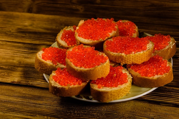 Sandwiches with red caviar on wooden table