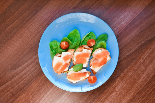 Sandwiches with red fish on a blue plate. decorated with greens