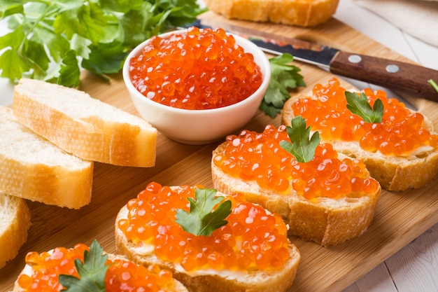 Sandwiches with red salmon caviar on a wooden Board. White table top.