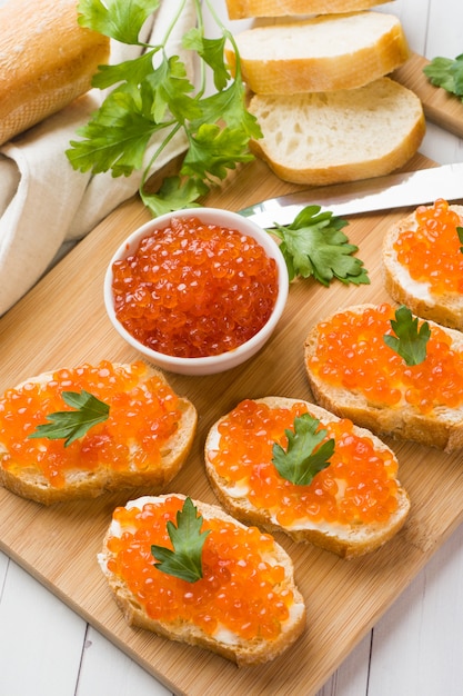 Sandwiches with red salmon caviar on a wooden Board. White table top.