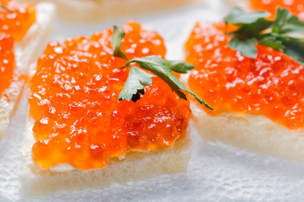 Sandwiches with salmon red caviar and herbs on white napkin