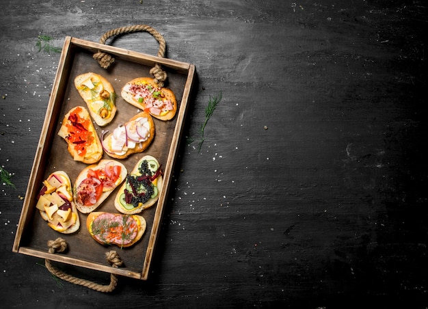 Photo sandwiches with seafood, meat and vegetables on fresh bread on the black chalkboard