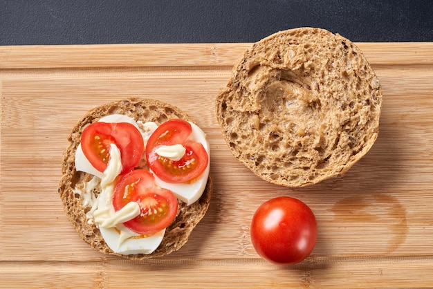 Sandwiches with tomatoes eggs and mayonnaise on a wooden plate