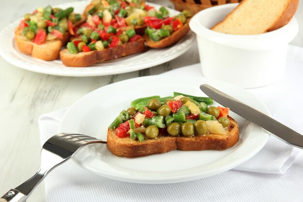 Sandwiches with vegetables and greens on plate on wooden table closeup