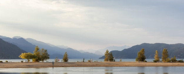 Sandy beach on the lake with canadian mountain landscape in background