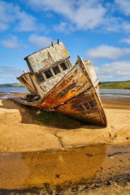 Photo sandy beach with abandoned shipwreck falling apart