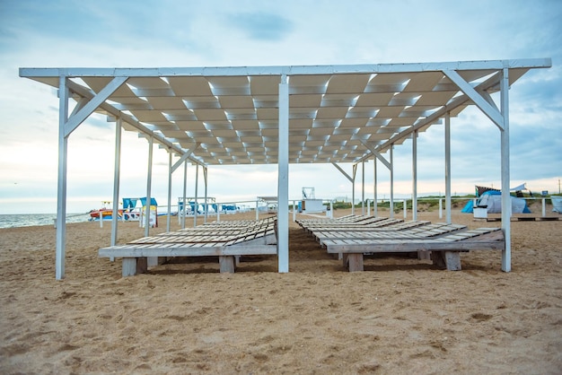 Sandy beach with sun loungers and a wooden canopy in a tropical resort on the sea coast Quarantine