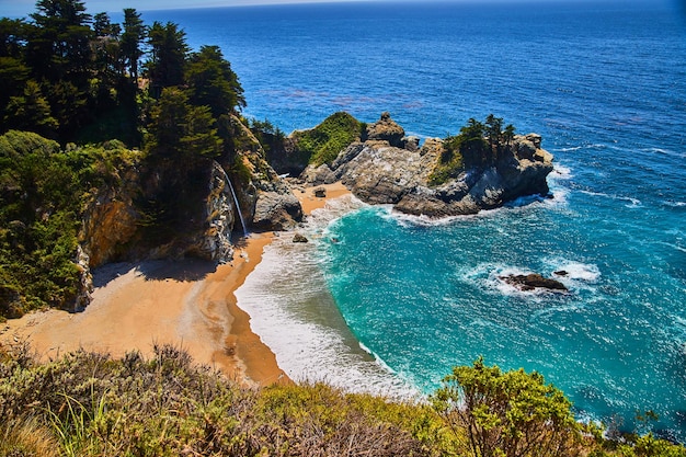 Sandy beaches and coastal rocks surround hidden waterfall in this ocean cove