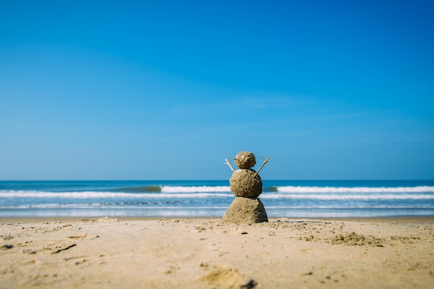 Sandy happy  man on the sea beach against blue cloudy summer sky - travel concept.