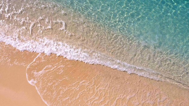 Sandy shore washing by clear turquoise waves aerial view from above summer paradise