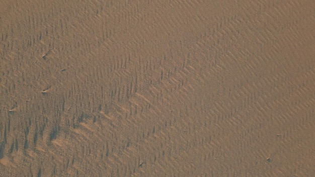 Sandy sunset beach texture top view aerial zoom out wind marks on wet sand