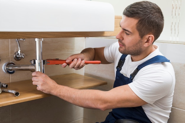 Sanitary technician using wrench on sink