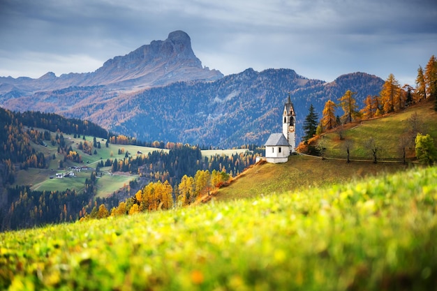 Santa Barbara church at the autumn Dolomite Alps Amazing landscape with small chapel on sunny meadow at San Genesio village location Province of Bolzano South Tyrol Italy