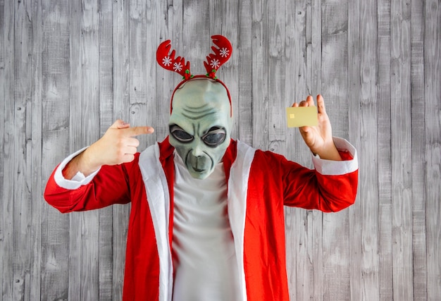 Santa Claus in alien costume pointing to a credit card