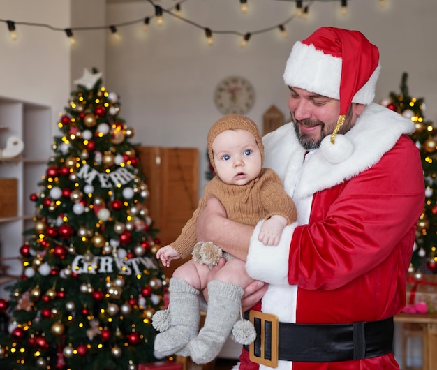 Santa Claus and baby on background of Christmas tree Happy new year and merry christmas Christmas family