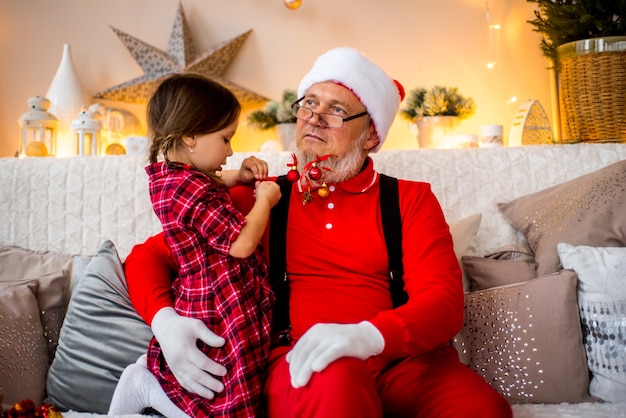 Santa Claus and child at home against Christmas tree. Family holiday concept.