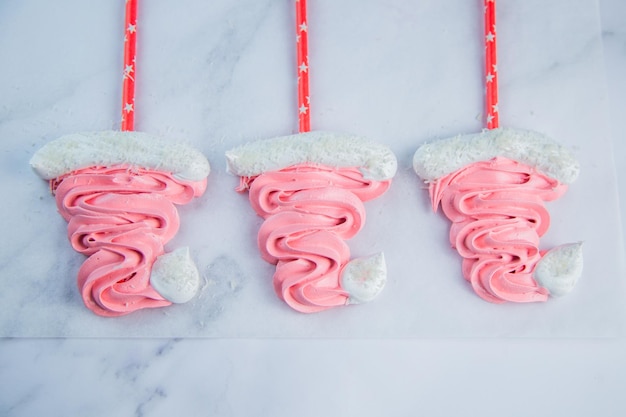 Santa claus christmas hats made of pink bizet on red sticks are lying on baking paper high quality p...