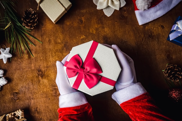 Santa Claus closeup shot of hands wearing white gloves holding a Christmas present