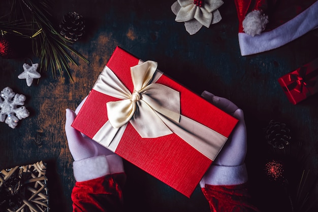 Santa Claus closeup shot of hands wearing white gloves holding a Christmas present