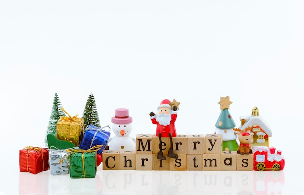 Santa Claus doll on merry Christmas wooden word and many Christmas decorations on white background