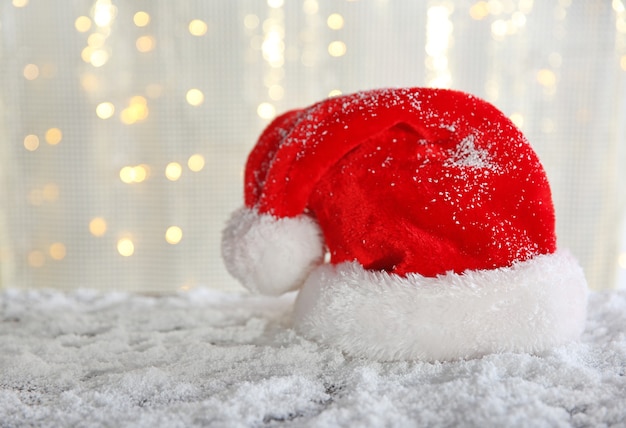 Santa Claus hat on a snowy table over glitter background