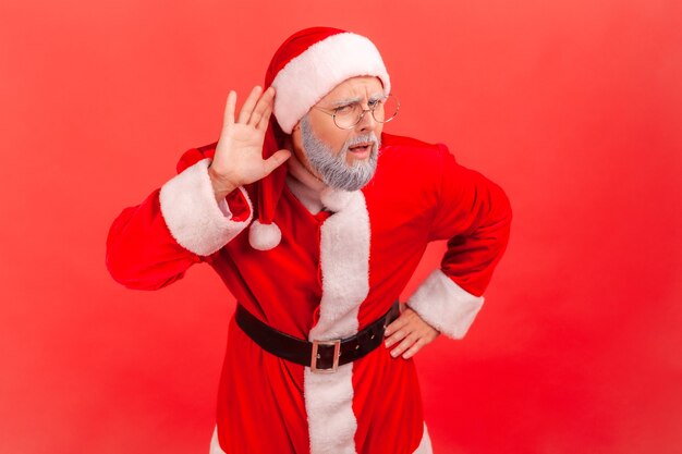 Santa claus holding hand near ear, listening to interesting talks and private secrets.