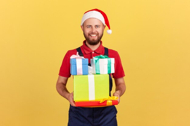 Santa claus new year hat on head holding many gift boxes, delivery of holiday presents.