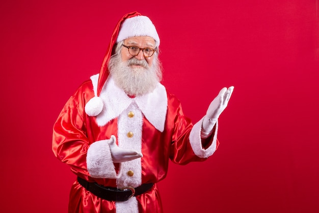 Santa Claus pointing aside, advertising Christmas promotion, New Year Christmas discount advertisement isolated on red background.