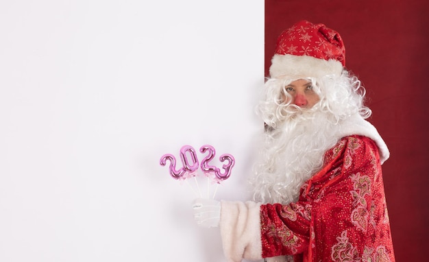 Santa Claus points to a white billboard