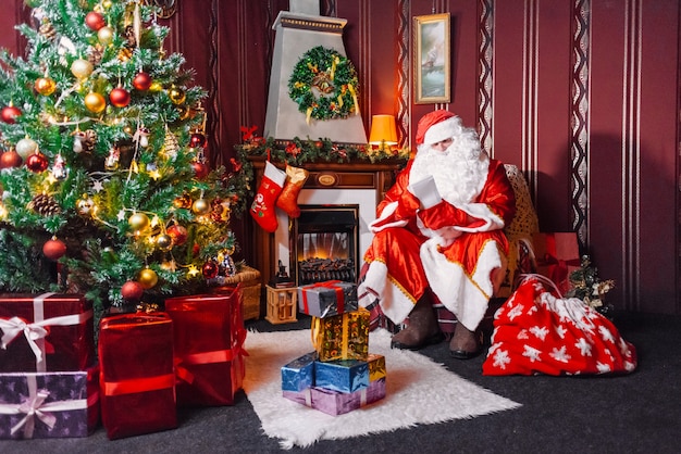 Santa Claus sitting next to a Christmas tree