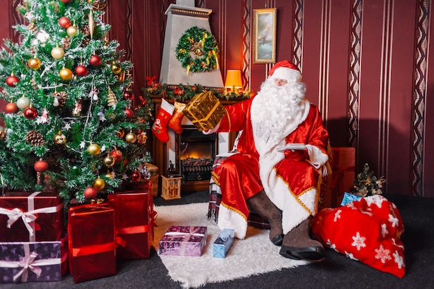 Santa Claus sitting next to a Christmas tree