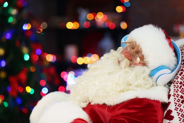 Santa Claus sitting with headphones sitting in comfortable rocking chair at home