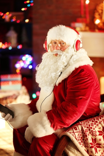 Santa Claus sitting with headphones sitting in comfortable rocking chair at home