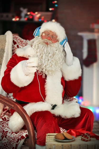 Santa Claus sitting with headphones sitting in comfortable rocking chair at home