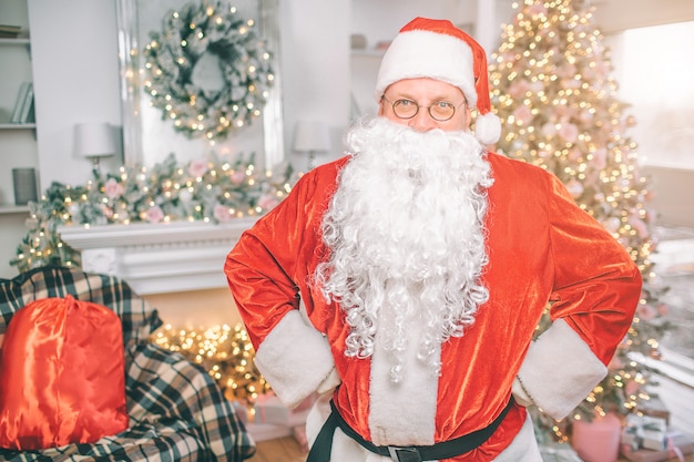 Santa Claus stands in a living room with Christmas decoration