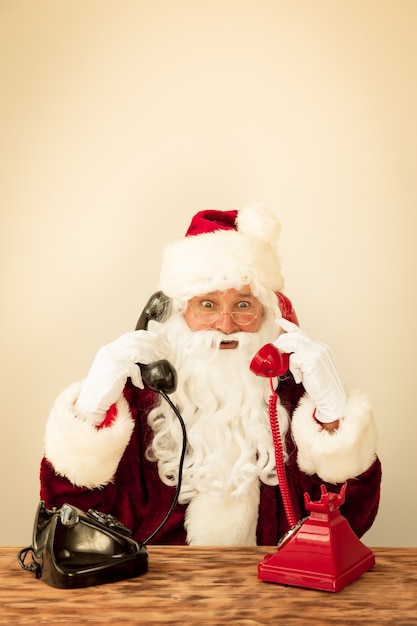 Santa Claus talking by phones. Christmas holiday concept