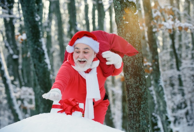 Santa claus walking to the winter forest with a bag of gifts snow landscape happy new year