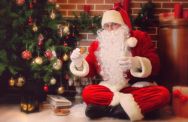 Santa Claus with gifts sitting next to a Christmas tree