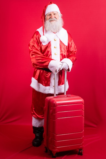 Santa Claus with his suitcase. New Year's travel concept. Santa Claus at the airport.