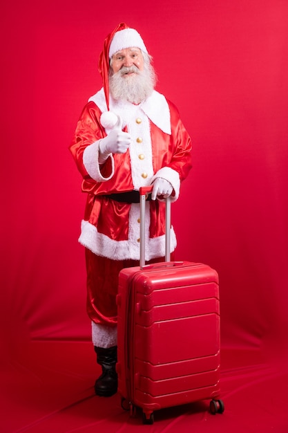 Santa Claus with his suitcase. New Year's travel concept. Santa Claus at the airport.