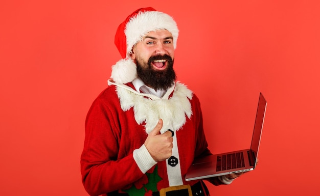 Santa claus with laptop showing thumb up online shopping modern technology new year christmas